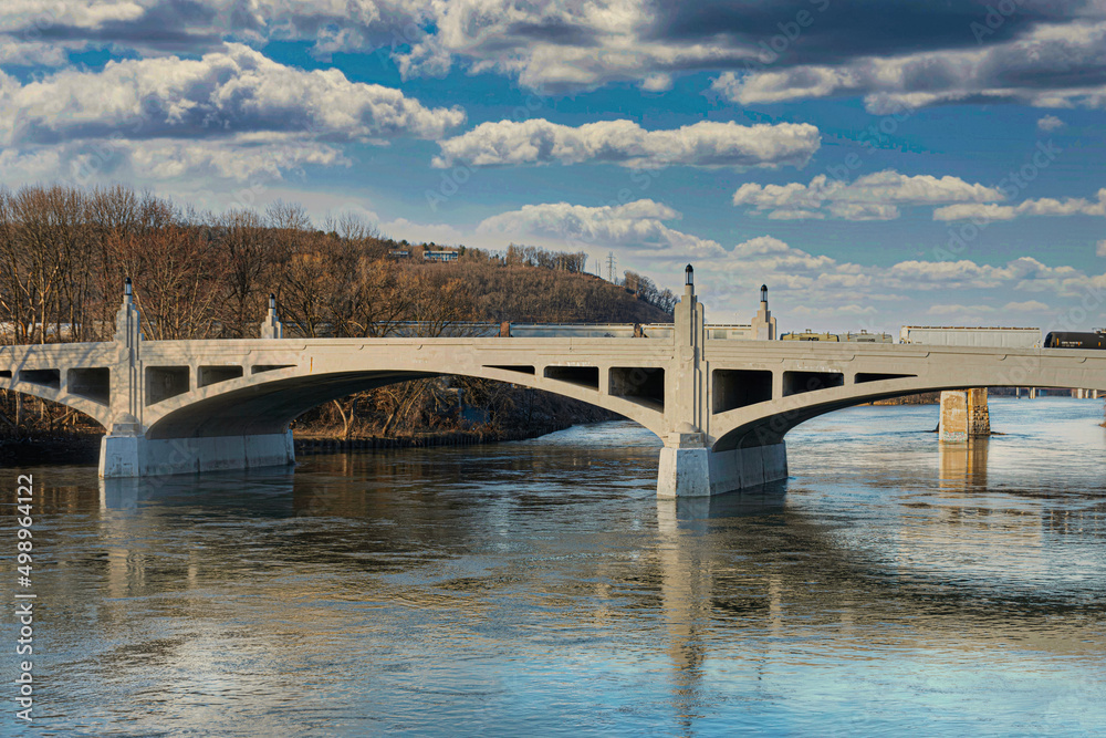 Fototapeta premium Clinton Street Bridge, which spans the Chenango River, in Binghamton in Upstate NY. Blue sky with darker storm clouds moving in of the bridge. 