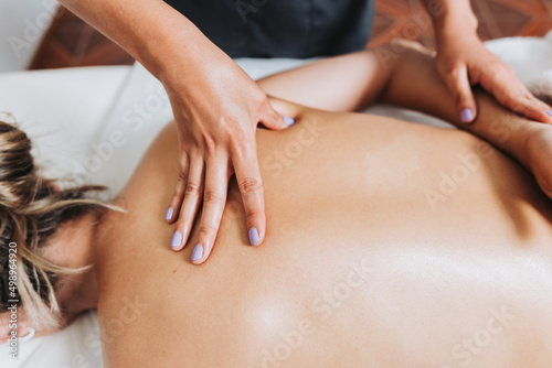 Unrecognizable therapist making back and spine massage to a female patient. Wellness center spa. Skin care.