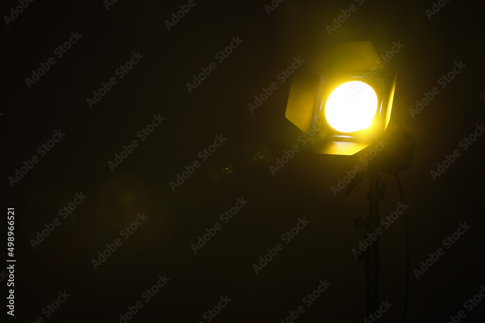 Bright yellow spotlight in darkness, space for text Bright yellow spotlight in darkness, space for text
