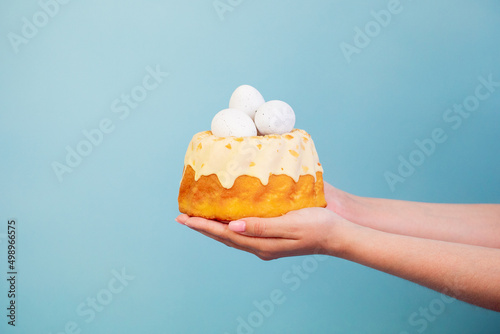 Easter cake with eggs in hands on blue background. Polish babka - traditional Easter funnel cake photo
