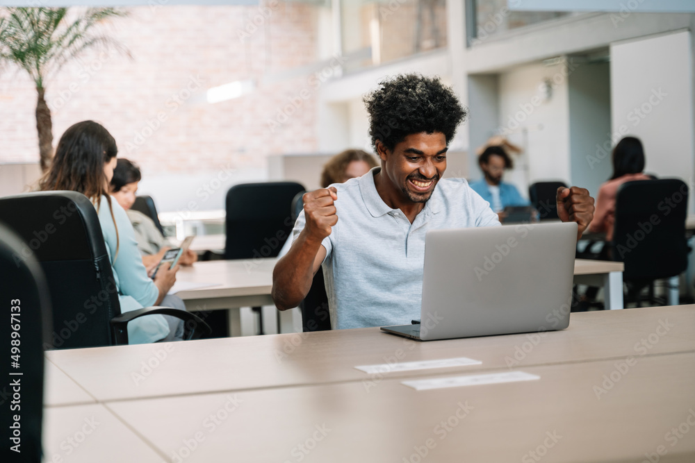 Happy young African business man freelancer man celebrating success and professional achievement in the office