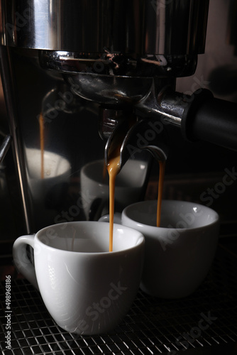 Making fresh aromatic espressos using professional coffee machine in cafe, closeup photo