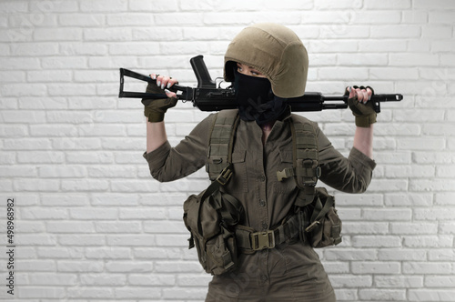 Fototapeta A Ukrainian girl soldier in a helmet and military ammunition with a Kalashnikov