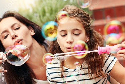 Having bubbles full of fun. A happy mother and daughter spending time together outdoors.