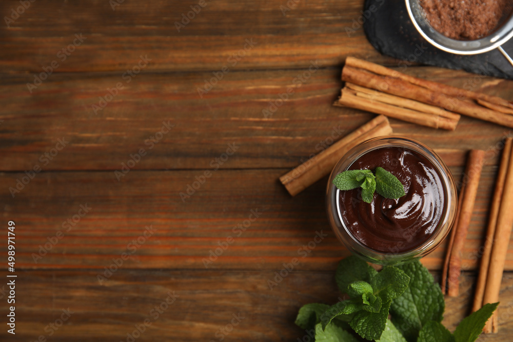 Glass of delicious hot chocolate with fresh mint and cinnamon sticks on wooden table, flat lay. Space for text Glass of delicious hot chocolate with fresh mint and cinnamon sticks on wooden table, flat lay. Space for text