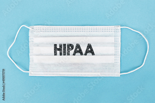 Word HIPAA Health Insurance Portability and Accountability Act printed on a white medical mask over blue background.