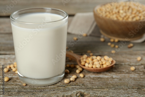 Glass with fresh soy milk and grains on wooden table, closeup