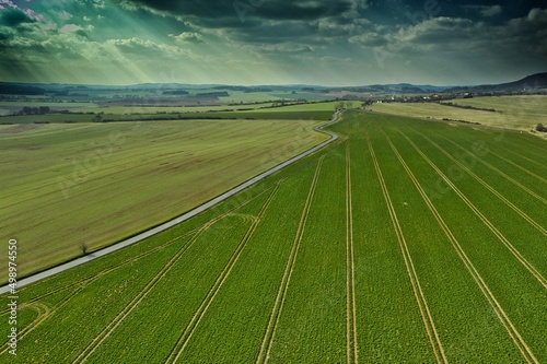 Green fields under cloudy sky by the curved road © ondrejschaumann