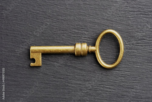 Bronze vintage antique key on black wooden background. Old keys concept © zah108