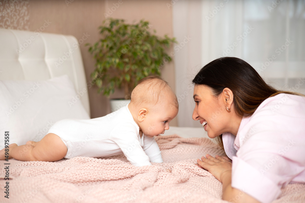 A beautiful young mother plays and cuddles with her baby in her bedroom on the bed. Love. motherhood Weasel tenderness. Lifestyle A beautiful young mother plays and cuddles with her baby in her bedroom on the bed. Love. motherhood Weasel tenderness. Lifestyle