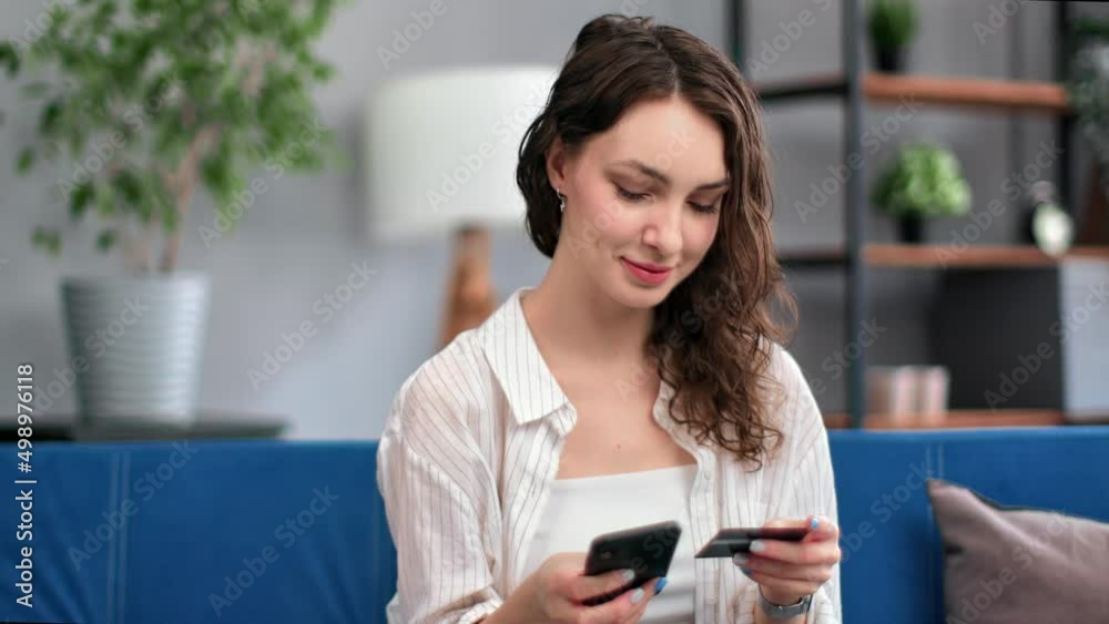 Closeup smiling curly woman paying card online shopping smartphone application on couch at home Closeup smiling curly woman paying card online shopping smartphone application on couch at home