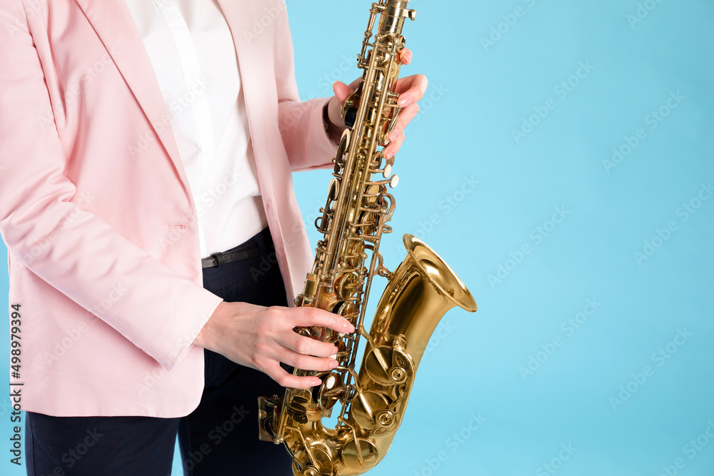 Obraz premium Woman with saxophone on light blue background, closeup. Space for text