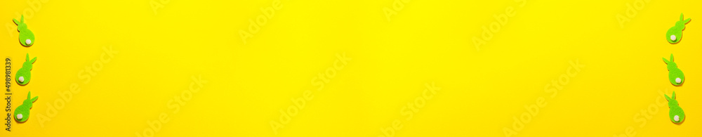 Fototapeta Banner of green velvet Easter bunnies on yellow background on the right and left with copy space. Flat lay top view holidays concept.