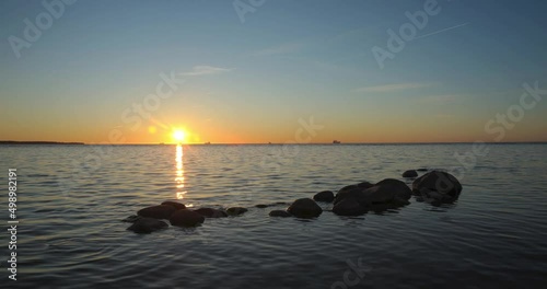 Time lapse slow beautiful sunset moving over the sea horizon. Composition with big rocks and reflection. High quality detailed colorful 4K