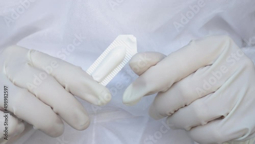 Suppositories in woman hands, white gloves. nurse or doctor, medical assistant, in white disposable robe holds a suppository in plastic pack. Suppository for anal or vaginal use. temperature, fever photo