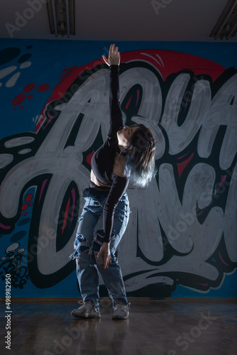 Female dancer in activewear squatting on the floor of modern dance studio and looking at you