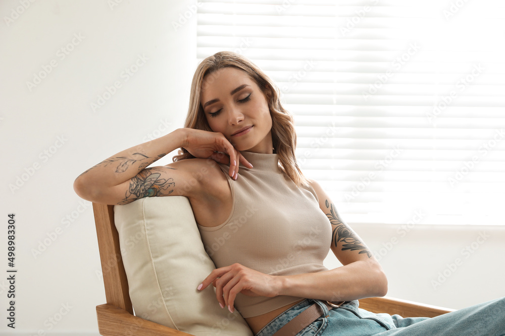 Beautiful woman with tattoos on arms resting at home