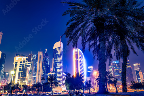 Night view in the city center of Doha, Qatar with many modern luxury buildings and skyscrapers illuminated with numerous lights.