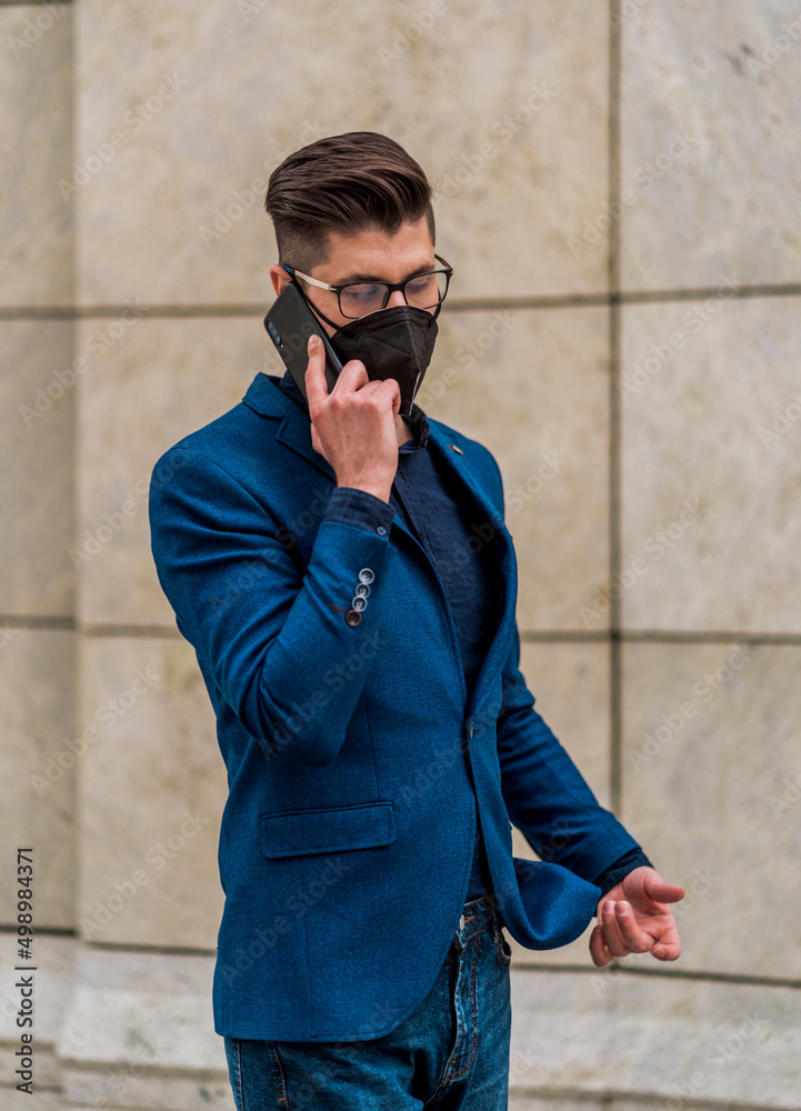 Obraz premium Stylish man wearing blue suit and denim pants walking on urban place
