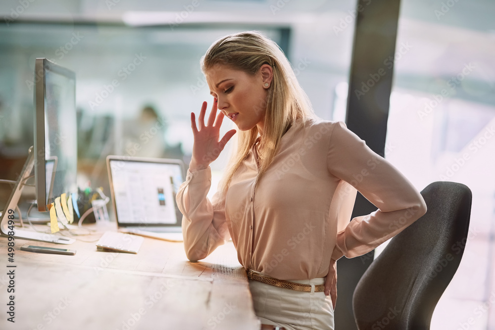 Ive been sitting for too long. Shot of a young businesswomen suffering from back pain while sitting at her desk in an office. Ive been sitting for too long. Shot of a young businesswomen suffering from back pain while sitting at her desk in an office.