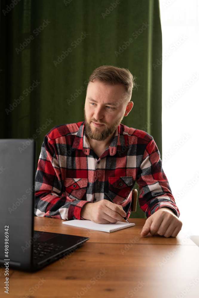 Adult student writes down information from a laptop while preparing for lecture on a university campus, a hipster works on a personal computer while sitting in a cafe, vintage color Adult student writes down information from a laptop while preparing for lecture on a university campus, a hipster works on a personal computer while sitting in a cafe, vintage color