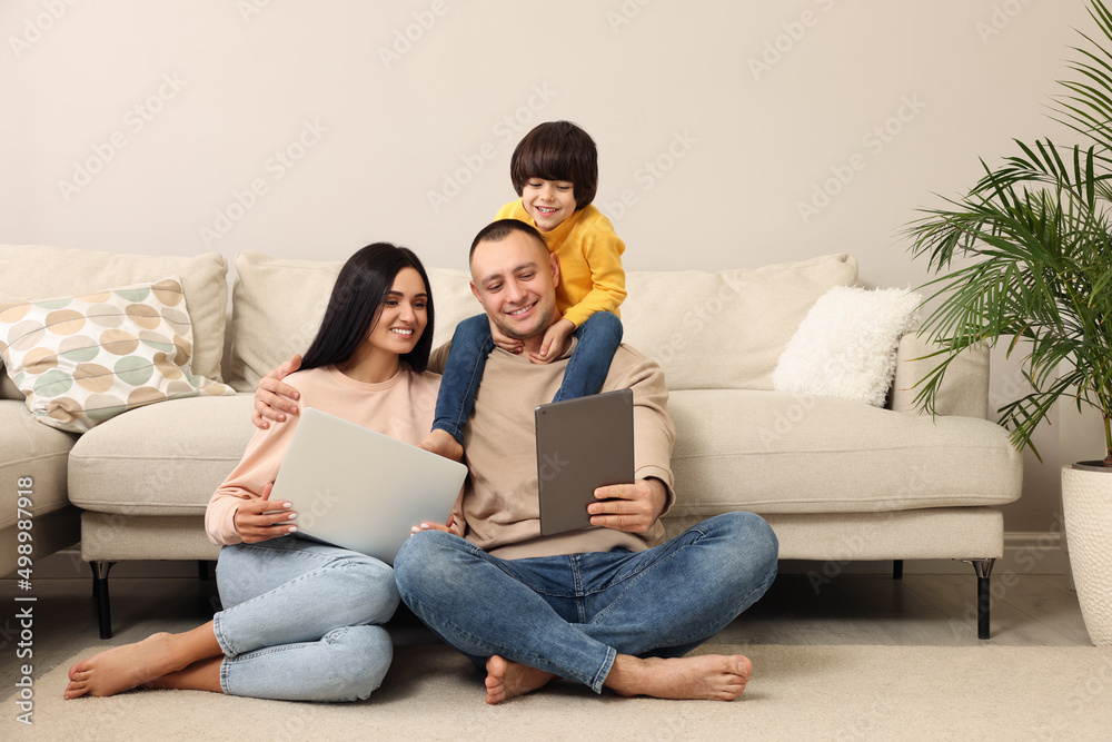 Happy family with gadgets on floor at home Happy family with gadgets on floor at home