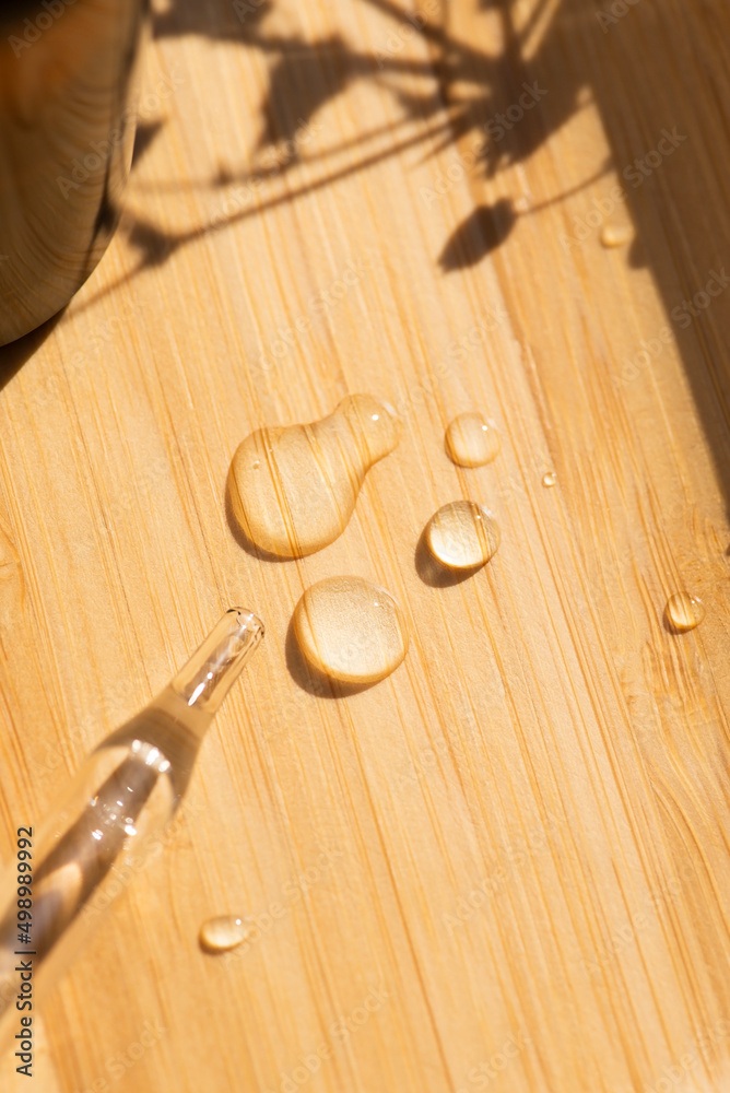 Pipette close-up with drops on the wooden surface in soft focus. Beautiful shadow in the sunlight. Skincare products, natural cosmetic. Beauty concept for face and body care Pipette close-up with drops on the wooden surface in soft focus. Beautiful shadow in the sunlight. Skincare products, natural cosmetic. Beauty concept for face and body care