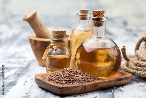 linseed essential oil in several glass bottles. Flax seeds in a wooden bowl.