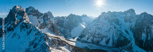Panoramic view of sun shining over snow covered mountain range during winter © Aerial Film Studio