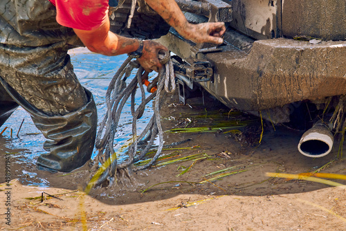 The 4x4 off road got stuck in a huge puddle of mud. Extreme car sports. An athlete prepares a winch for the evacuation of a four-wheel drive car from a trap