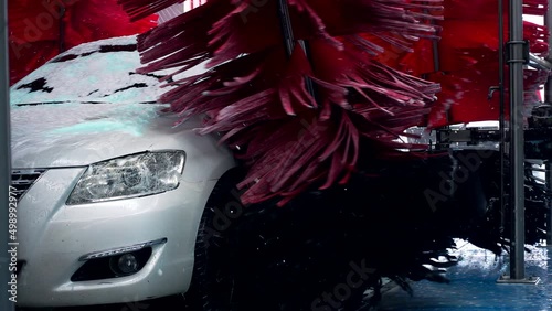 White car moving though automatic car wash machine. The brush moving to clean the car. Slow motion shot