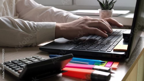 Desktop. men's hands in a shirt are typing on a laptop keyboard.the man at the desk. work in the office