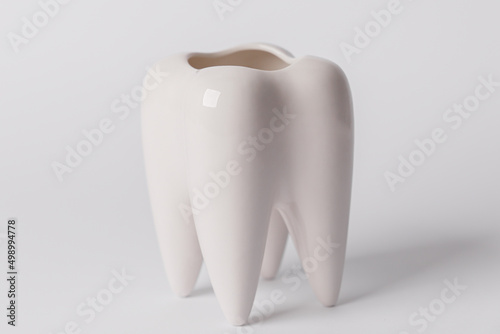 Fototapeta Naklejka Na Ścianę i Meble -  The concept of dental health and dental care. Dentist's day. A white tooth on a white background. A healthy tooth. Space for text. Close-up