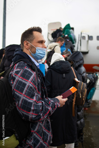 Passengers board the plane. Masked people board the flight. Travel during quarantine. A passenger in mask.