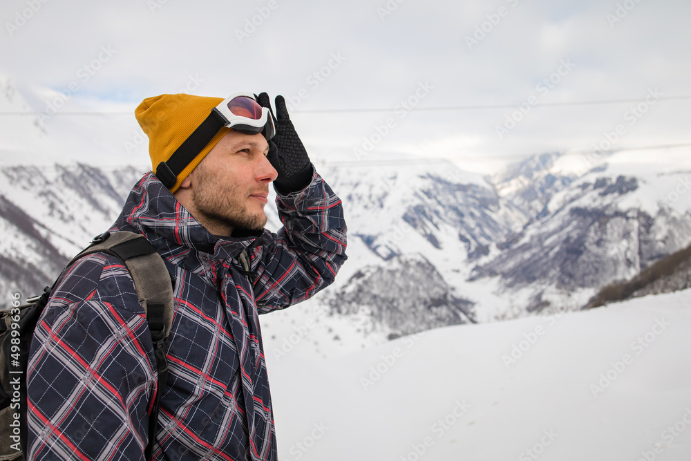 Active tourist with backpack enjoying the view on top of snowy mountain.