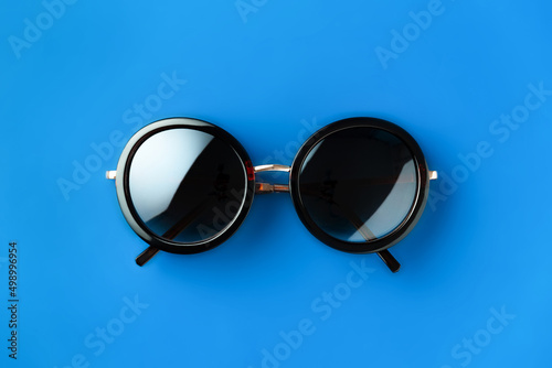 Round hipster sunglasses on blue background in minimalist style