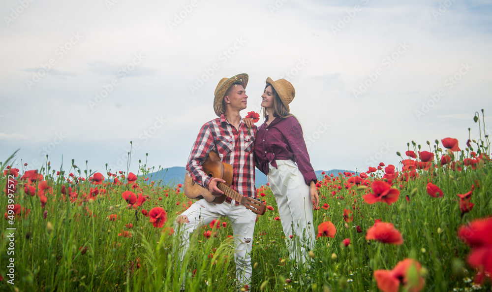 Man and woman embracing and kissing in poppy field on the dusk with guitar, music Man and woman embracing and kissing in poppy field on the dusk with guitar, music