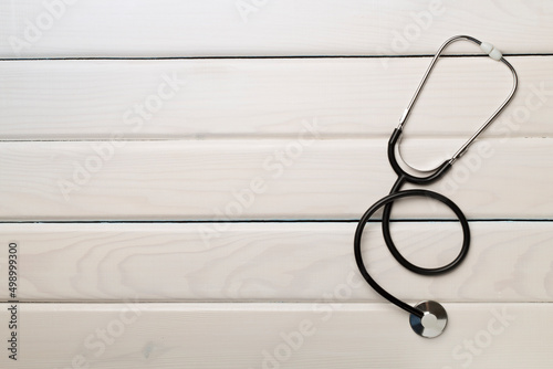 Stethoscope on wooden background, top view