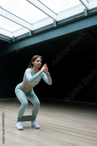 A young woman squats during a workout at home