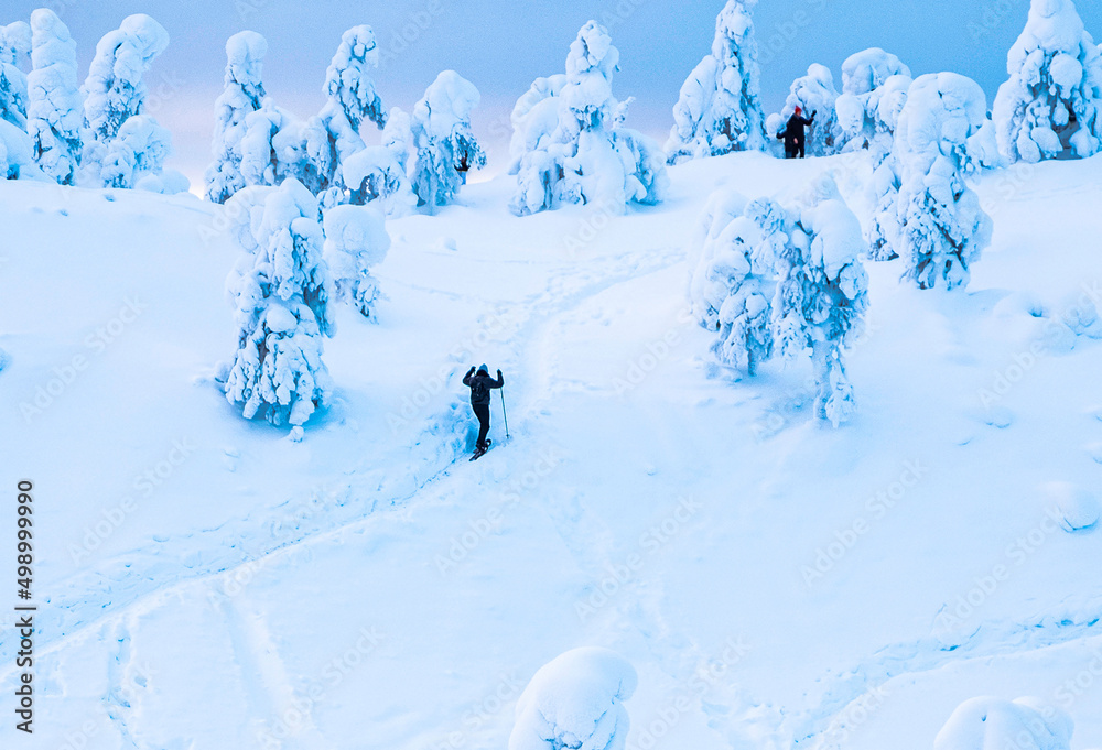 People walking on a snow-covered mountain in winter in Lapland