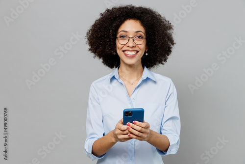 Young happy employee business corporate lawyer woman of African American ethnicity in classic formal shirt work in office hold in hand use mobile cell phone isolated on grey color background studio.