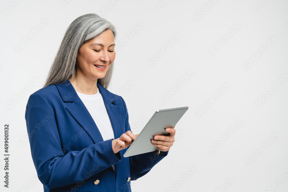 Happy confident mature middle-aged businesswoman teacher tutor freelancer bank manager employee CEO boss in formal suit working on digital tablet, searching information online, watching webinars Happy confident mature middle-aged businesswoman teacher tutor freelancer bank manager employee CEO boss in formal suit working on digital tablet, searching information online, watching webinars