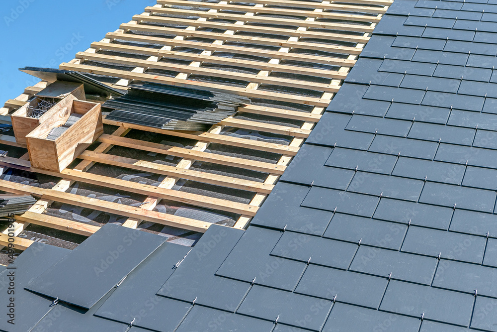 Image of a construction site covering a slate roof of a house. - obrazy, fototapety, plakaty 