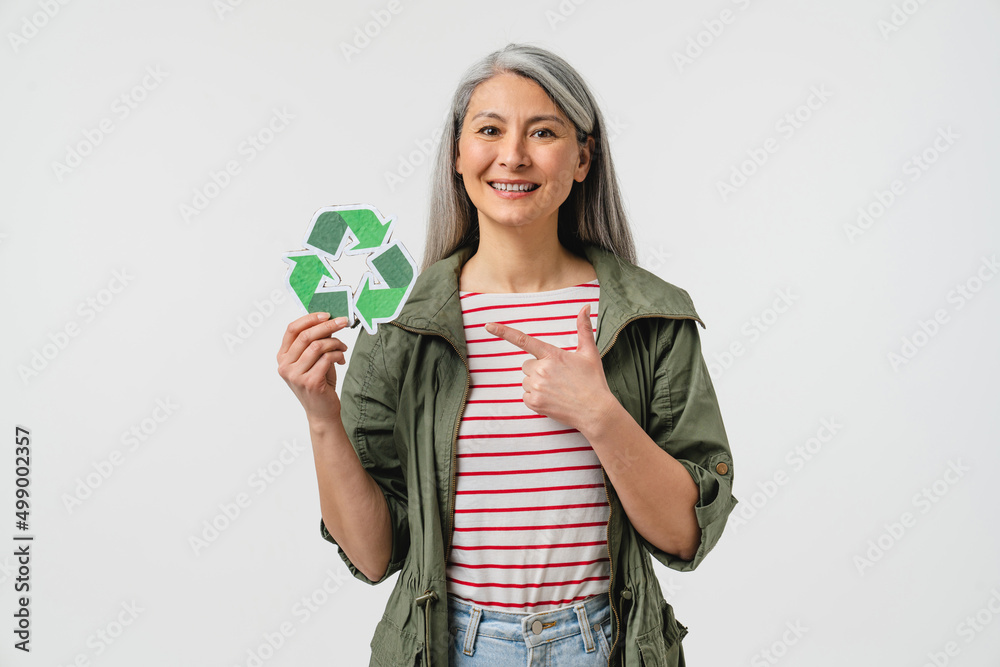 Middle-aged woman eco-activist pointing at recycling logo sign isolated in white background.Sorting garbage plastic bottles, saving planet from contamination. Ecology environmental reservation problem Middle-aged woman eco-activist pointing at recycling logo sign isolated in white background.Sorting garbage plastic bottles, saving planet from contamination. Ecology environmental reservation problem