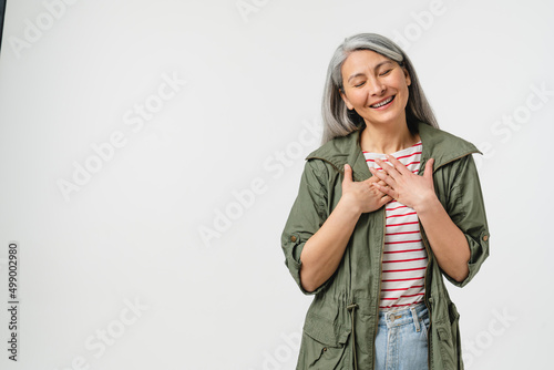Pleased touched with a compliment caucasian mature middle-aged woman in casual clothes listening to praise isolated in white background photo