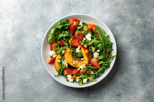 salad bowl with arugula, strawberry, cottage cheese, nectarine and peanut paste. healthy eating concept