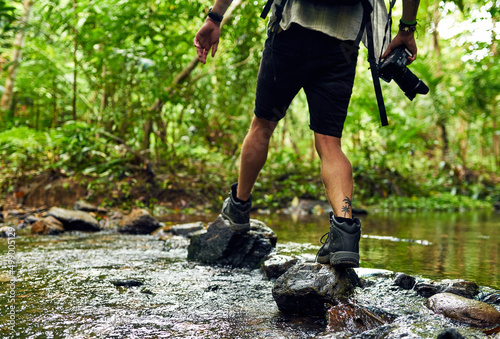 Go where the wild things are. Cropped shot of an unidentifiable hiker crossing a stream while exploring in the woods.
