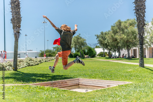 Lisboa, Portugal - July 22 2016: Kid jumping over a small fountain in a park.