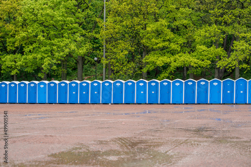 A row of portable toilets in front of a forest.. photo