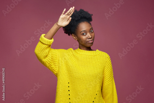 Confident stylish young african american woman with afro hair saluting, showing respect, doing honour gesture photo